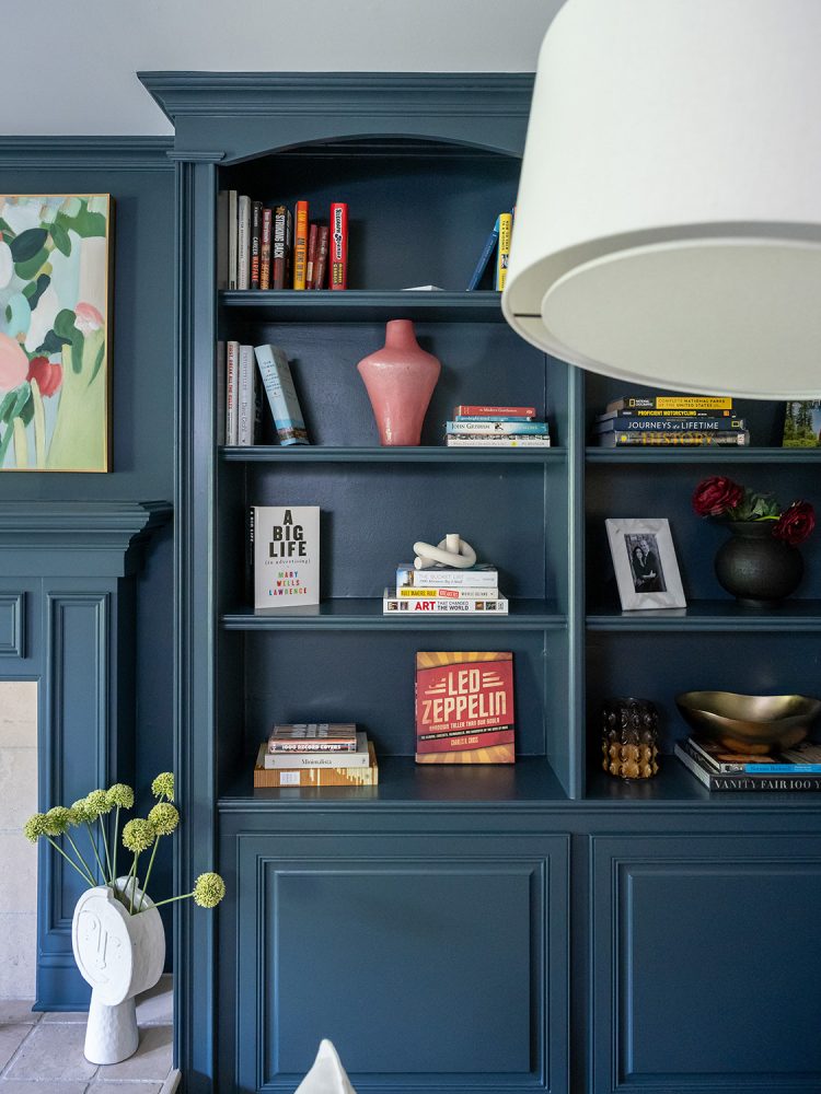 Books, photo frames, and objects are arranged on blue bookshelves.