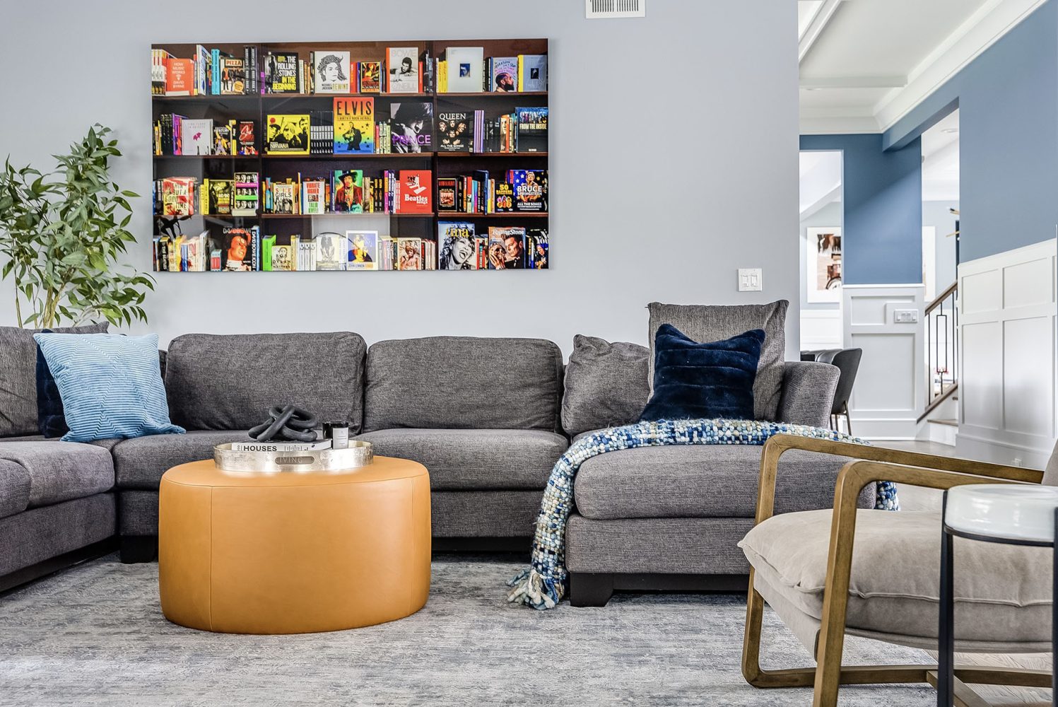 A grey modular couch is shown beneath a colorful framed image of a bookshelf. Many of the books pictured are front-facing biographies of famous rock and roll artists.