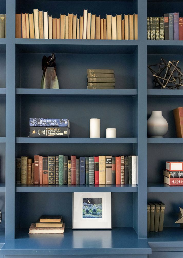 Books and objects are arranged in different ways on medium blue bookshelves.